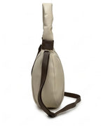 Beige sling bag with brown strap on a white background