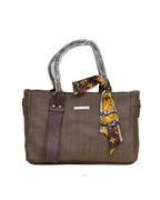 Brown handbag with a patterned scarf draped over the handle on a white background