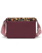 Maroon handbag with floral top flap and patterned strap on a white background